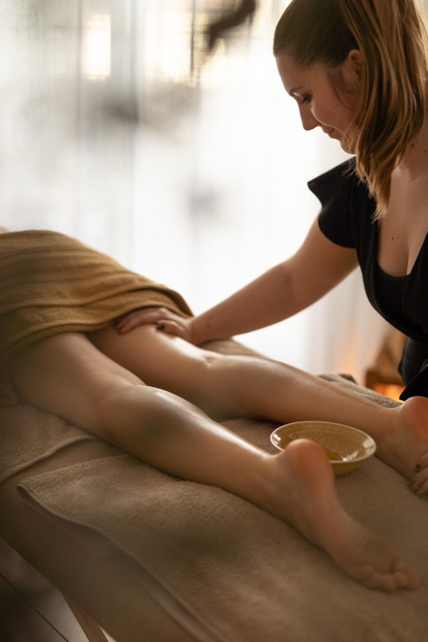Massage des jambes à l'huile, bol en céramique posé sur la table