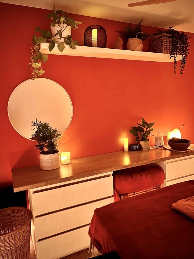 Le mur terracotta du salon : miroir rond, plantes et bougies posées sur la console